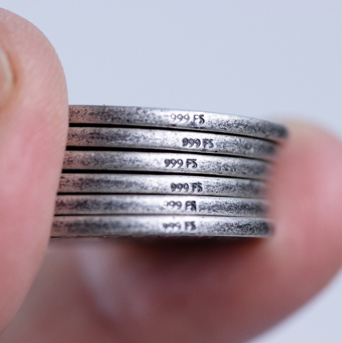 Edges of silver coin photographed, depicting the text .999 FS, which stands for .999 fine silver