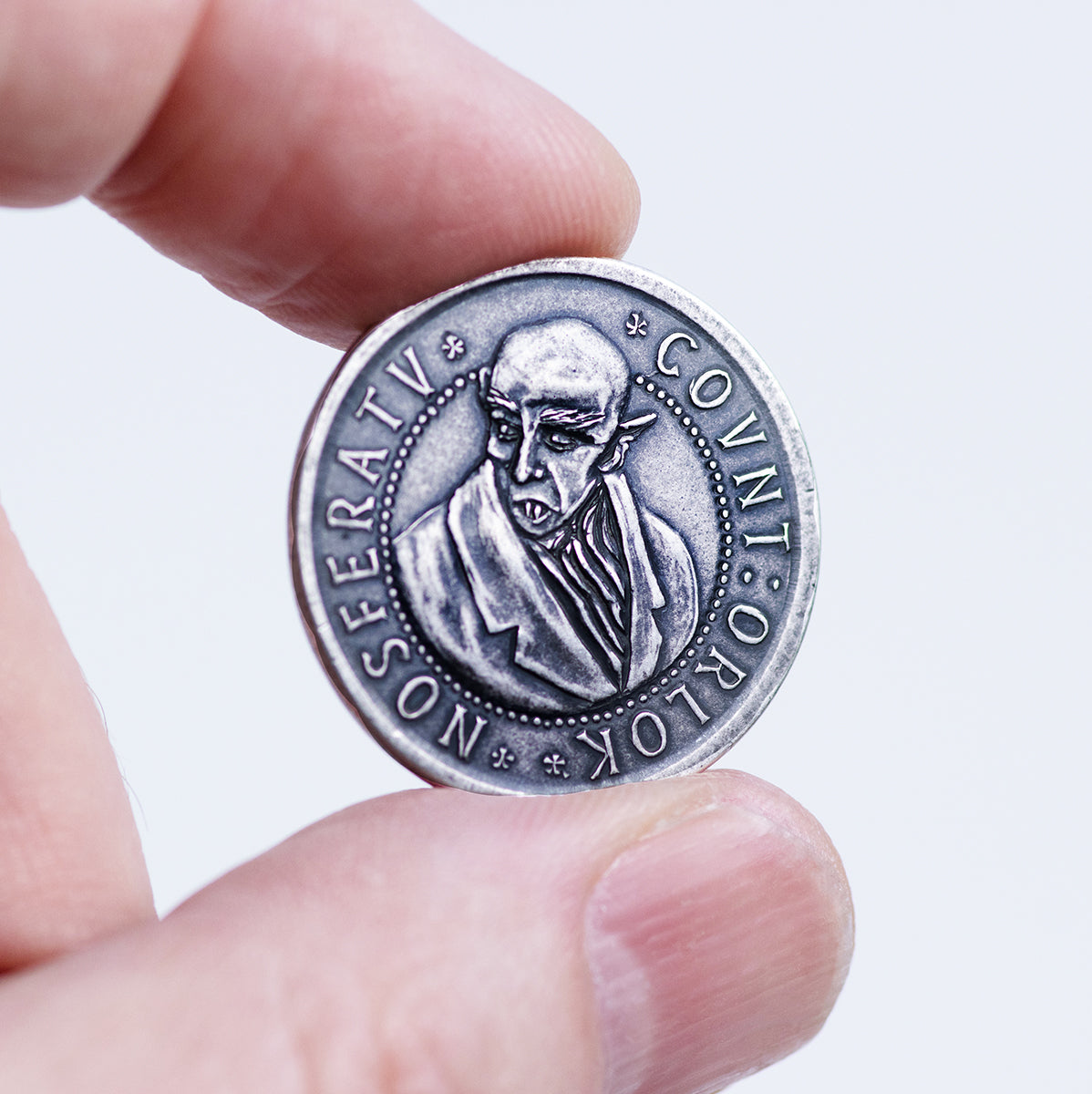 Silver coin being held up depicting Max Schreck's likeness as Count Olaf in F.W. Murnau's 1922 silent film, Nosferatu