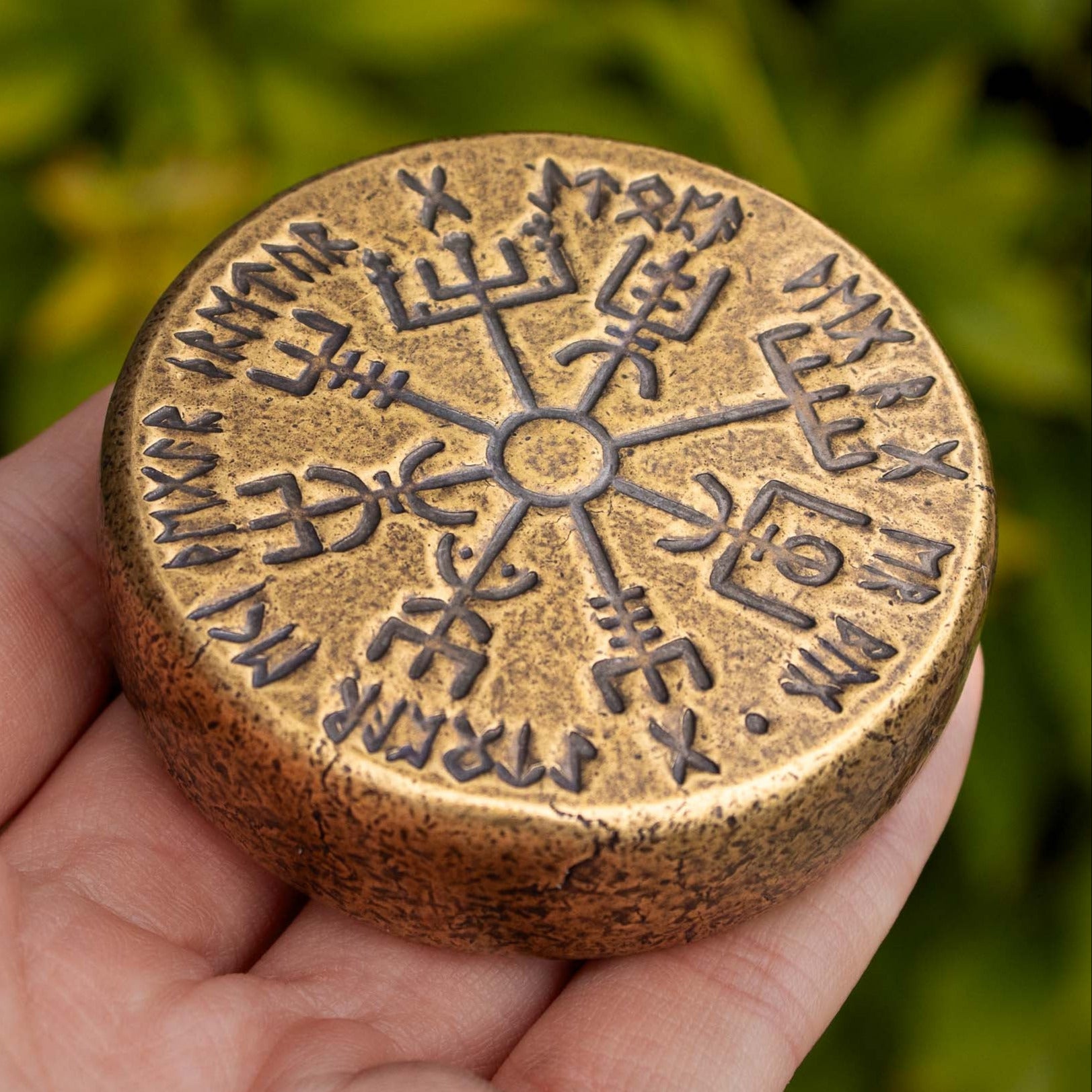 a giant bronze vegvisir held in the hand